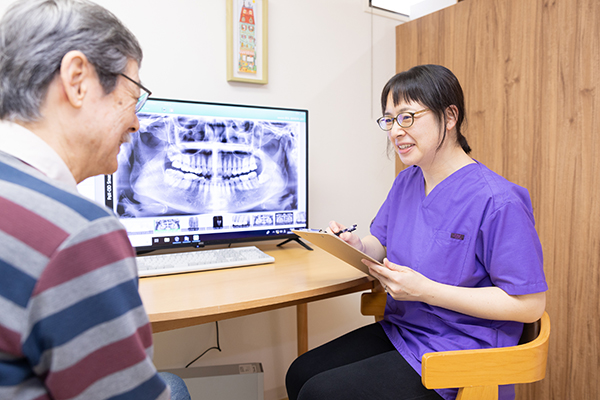 レントゲン画像を見ながら説明する歯科医師