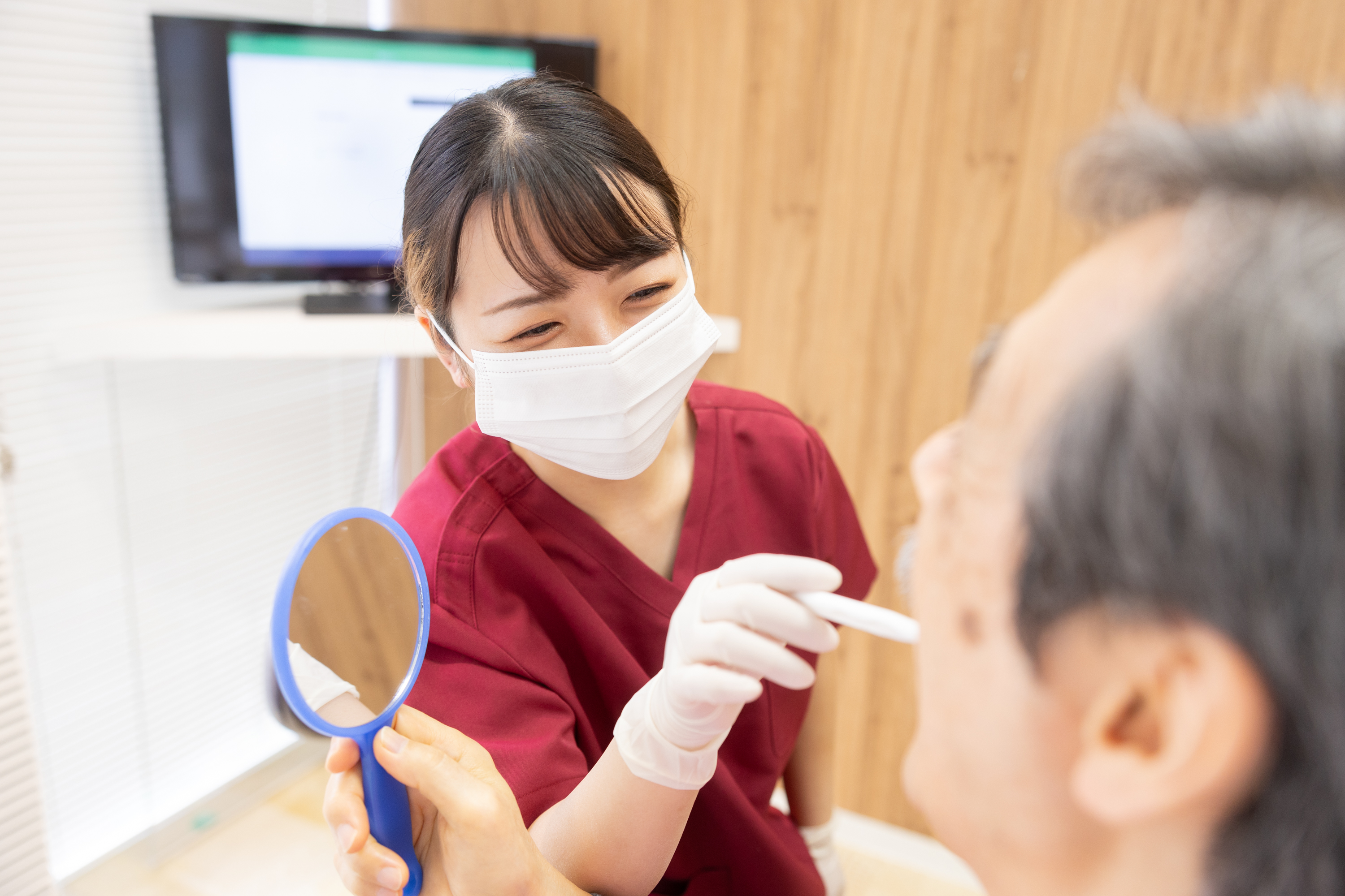新生歯科医院のスタッフが患者さんに鏡を見せながら丁寧に説明している様子